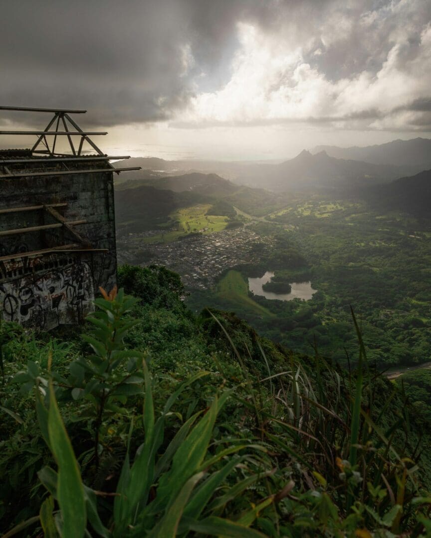 A misty, lush valley viewed from a high cliff with ruins in the foreground.