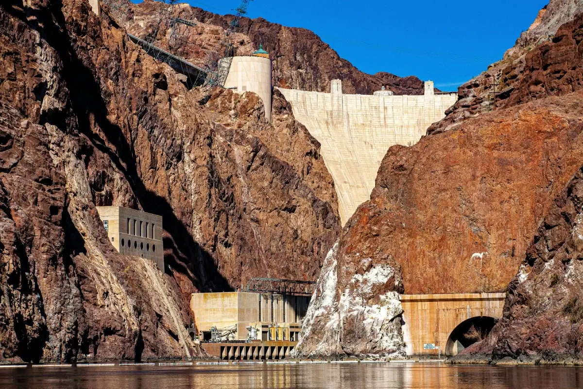 Hoover Dam nestled between rocky cliffs under a partly cloudy sky.