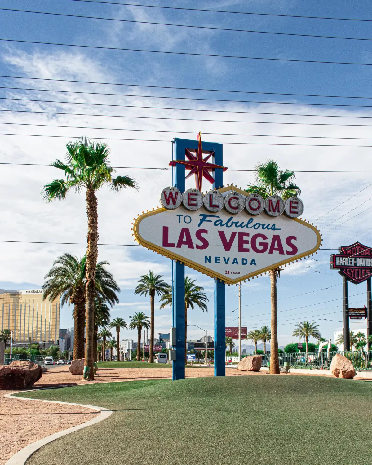 Iconic Welcome to Fabulous Las Vegas sign with palm trees under a blue sky.
