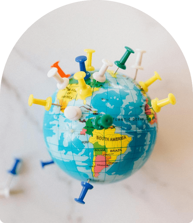 A globe with colorful push pins stuck around it.