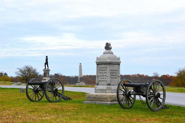 Historic cannons and monuments at a battlefield site with a distant obelisk.
