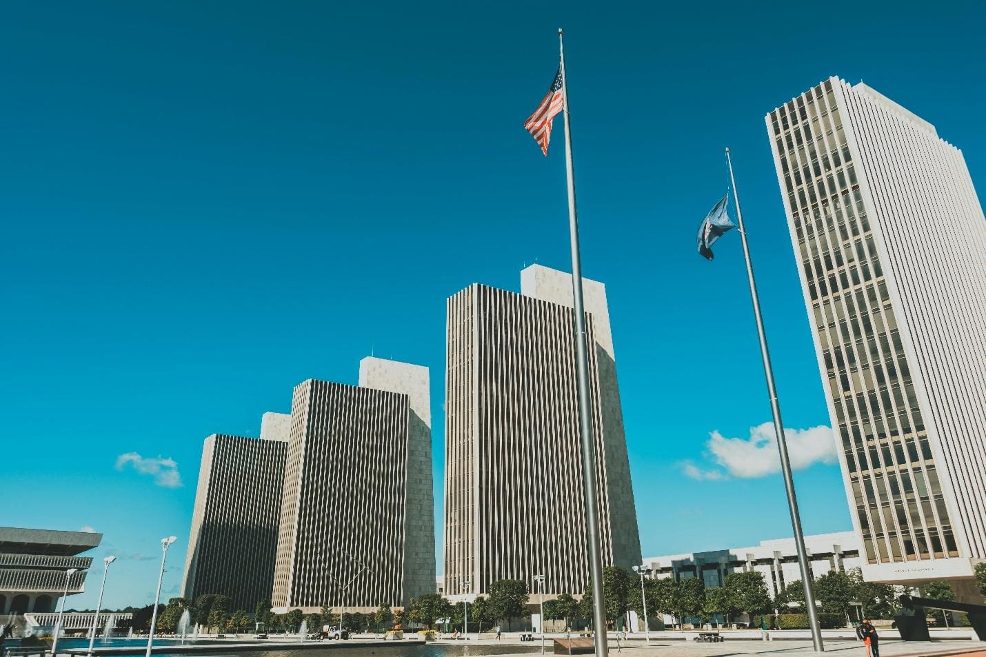 Tall buildings under a clear blue sky with a raised flag.